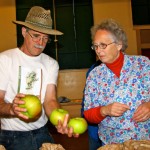 Harry Burton and Jill Willmott are discussing which of these apples best represents the apple variety, Bramley Seedling. This happens when more than one bag of a variety are submitted. Photo by Jan Mangan